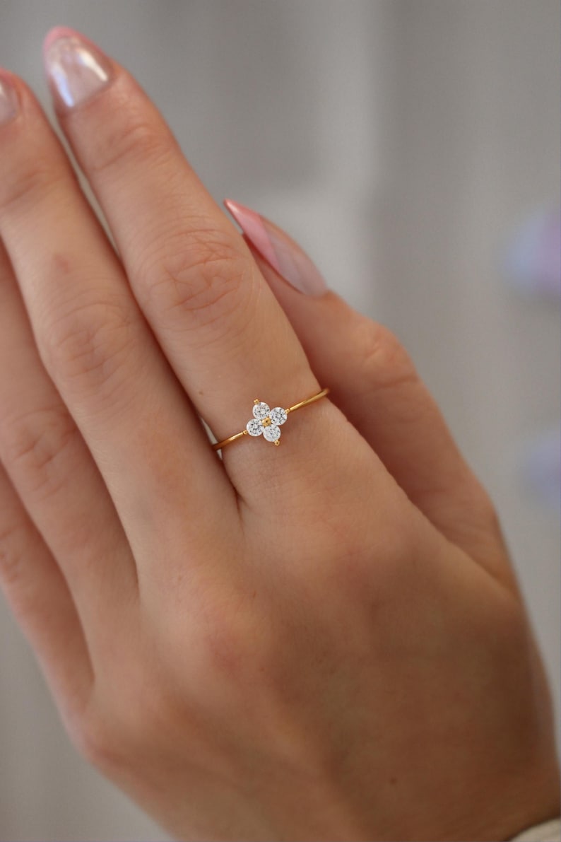 May include: A gold ring with a cluster of small, clear stones set in a flower shape.