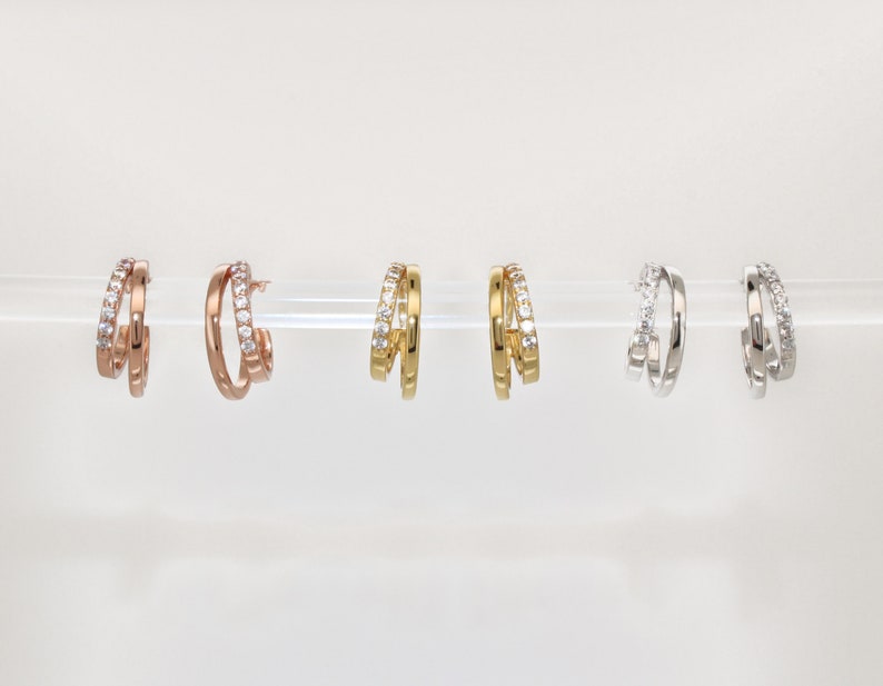 K&ouml;nnte beinhalten: Drei Paar Creolen mit einem Doppelband-Design. Die Ohrringe sind in Ros&eacute;gold, Gold und Silber erh&auml;ltlich.