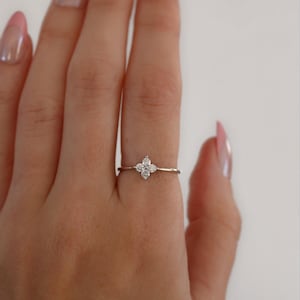 May include: A delicate silver ring with a small, four-leaf clover design set with clear sparkling stones.