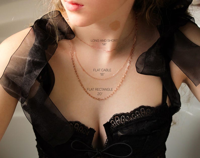 May include: Three gold necklaces of different lengths and styles on a model's chest. The necklaces are labeled "Long and Short 14", "Flat Cable 18", and "Flat Rectangle 20".