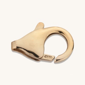 May include: Gold-toned metal clasp with a spring-loaded closure. The clasp has a smooth, polished finish and is marked "14/20".