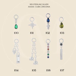 May include: A selection of 925 sterling silver charms with cubic zirconia and gemstone details. Designs include a teardrop, starburst, and dangling styles. Each charm is labelled with a number from 100 to 107.
