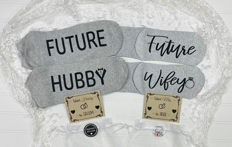 May include: Two pairs of grey socks with black text. One pair says "Future Hubby" and the other says "Future Wife" with a ring symbol. Each pair comes with a small card that says "Future Hubby - The Groom" and "Future Wife - The Bride".