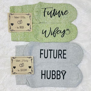 May include: Two pairs of socks with text printed on them. One pair is green with the text "Future Wifey" and the other pair is grey with the text "FUTURE HUBBY".
