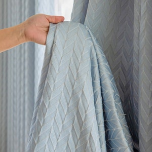 May include: A light blue curtain with a chevron pattern. The curtain is made of a soft, textured fabric.