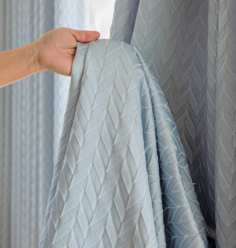 May include: A light blue curtain with a chevron pattern. The curtain is made of a soft, textured fabric.