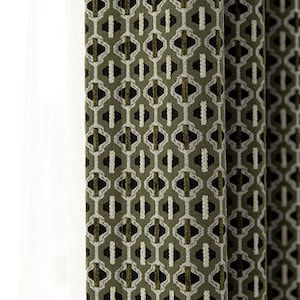 May include: Close-up of olive green and black patterned fabric, likely a curtain or drapery. The design features repeating geometric shapes in black, white, and olive green. The fabric is textured and appears to be made of a woven material.