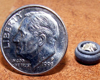 May include: A silver US dime coin with the words "Liberty" and "In God We Trust" and the year 1998. The coin is next to a miniature black ceramic bowl filled with smaller silver coins.
