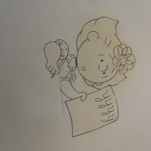 May include: A black and white line drawing of a girl with a flower in her hair, sitting at a desk and writing in a notebook.