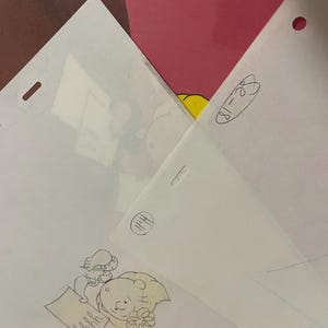 May include: A black and white pencil drawing of a cartoon character holding a piece of paper with the word "hrrhh" written on it. The character is wearing a flower in their hair and has a surprised expression on their face.