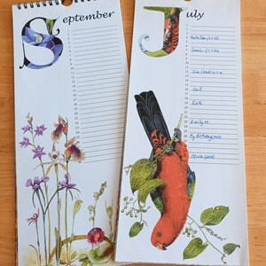 K&ouml;nnte beinhalten: Zwei Kalenderseiten, eine f&uuml;r September und eine f&uuml;r Juli. Die Septemberseite zeigt eine Blumenillustration mit lila Orchideen. Die Juliseite zeigt eine Illustration eines rot-schwarzen Vogels. Beide Seiten haben handschriftliche Namen und Daten.
