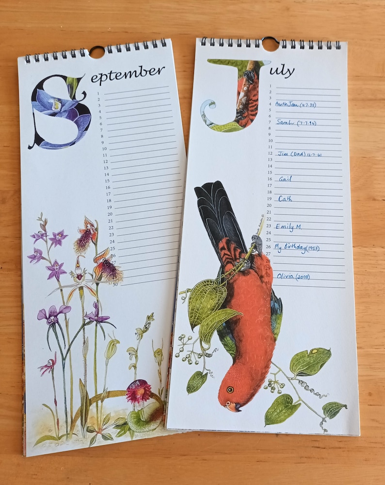 K&ouml;nnte beinhalten: Zwei Kalenderseiten, eine f&uuml;r September und eine f&uuml;r Juli. Die Septemberseite zeigt eine Blumenillustration mit lila Orchideen. Die Juliseite zeigt eine Illustration eines rot-schwarzen Vogels. Beide Seiten haben handschriftliche Namen und Daten.