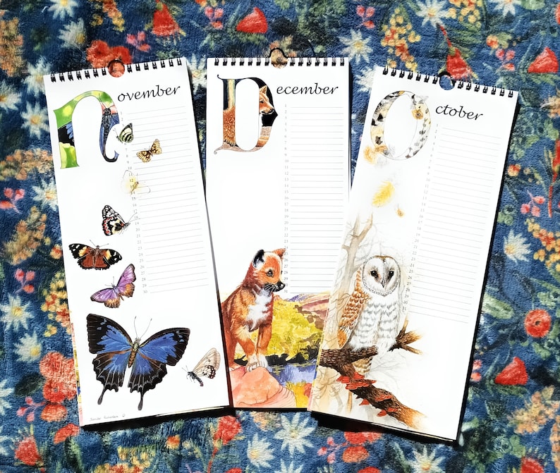K&ouml;nnte beinhalten: Drei farbenfrohe Kalenderbl&auml;tter mit Illustrationen von Tieren und Natur. Die Seiten sind mit "November", "Dezember" und "Oktober" beschriftet.