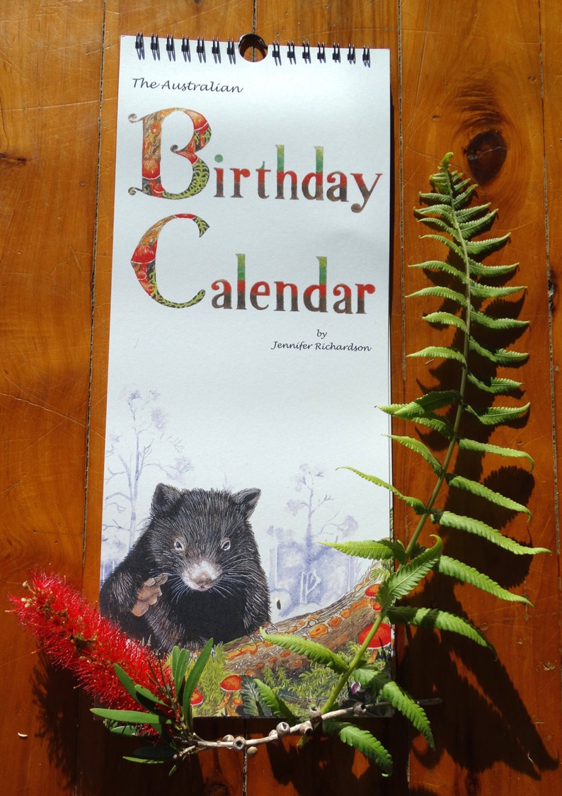 K&ouml;nnte beinhalten: Ein wei&szlig;er Kalender mit dem Text "The Australian Birthday Calendar by Jennifer Richardson". Der Kalender zeigt eine farbenfrohe Illustration eines Wombats in einer Waldlandschaft.