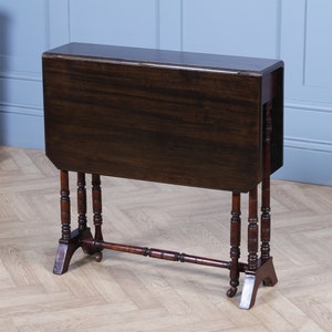May include: A dark brown wooden folding table with a simple design. The table has four legs with turned details and a single stretcher connecting the legs. The table top is rectangular and has a smooth finish.