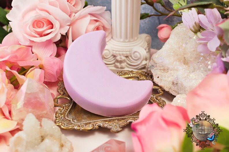 purple crescent moon shaped bar of soap surrounded by flowers and gemstones