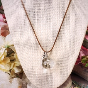 May include: A brown leather cord necklace with a silver pendant featuring a dandelion inside a clear glass orb.
