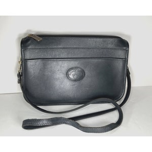May include: Black leather crossbody bag with a long strap. The bag has a rectangular shape with a top zipper closure and a front pocket. The brand name "MICHAEL G" is embossed on the front.