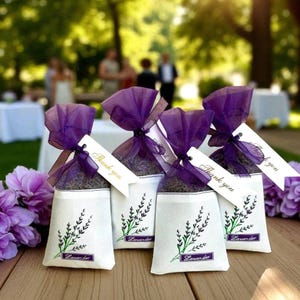 May include: Four small white fabric sachets filled with dried lavender, each tied with a purple organza ribbon and a white tag printed with the words Thank you. Each sachet features a green and purple lavender sprig illustration.