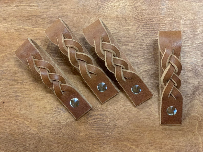 May include: Four brown leather braided drawer pulls with silver metal accents.