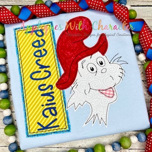 May include: A blue and yellow striped rectangle with the text "Kaiya Creed" in blue.  Next to it is a white cat with a red hat, white swirls, and a pink tongue sticking out.