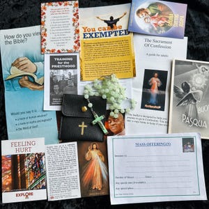 May include: Assortment of religious items including pamphlets, a rosary, and a small black leather case with a gold cross. The pamphlets have titles such as "The Sacrament of Confession" and "Mass Offering(s)".