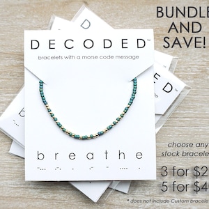 May include: A bundle deal for bracelets with a morse code message. The bracelets are made with green and gold beads. The text on the card reads "DECODED" and "breathe". The text on the card also reads "Bundle and Save!" and "3 for $27, 5 for $40".