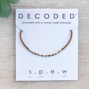 May include: Gold beaded bracelet with a white card that says "DECODED" bracelets with a morse code message and "s.p.e.w" with the morse code for each letter.
