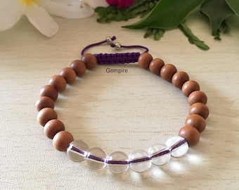 May include: A brown wooden beaded bracelet with a purple cord and clear quartz beads. The bracelet is tied with a knot and has a silver metal clasp. Gempire is written on the bracelet.