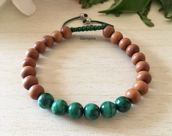 May include: A brown wooden bead bracelet with green malachite beads. The bracelet has a green cord with silver metal toggles.