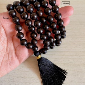 May include: A black wooden mala bead necklace with a black tassel. The beads are 10 mm in diameter. The necklace is 108 beads long. 10 mm.