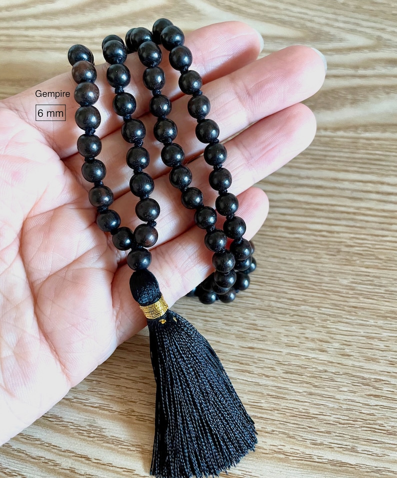 May include: Black wooden beaded necklace with a black tassel. The beads are 6 mm in diameter. Gemspire is written on the tag.