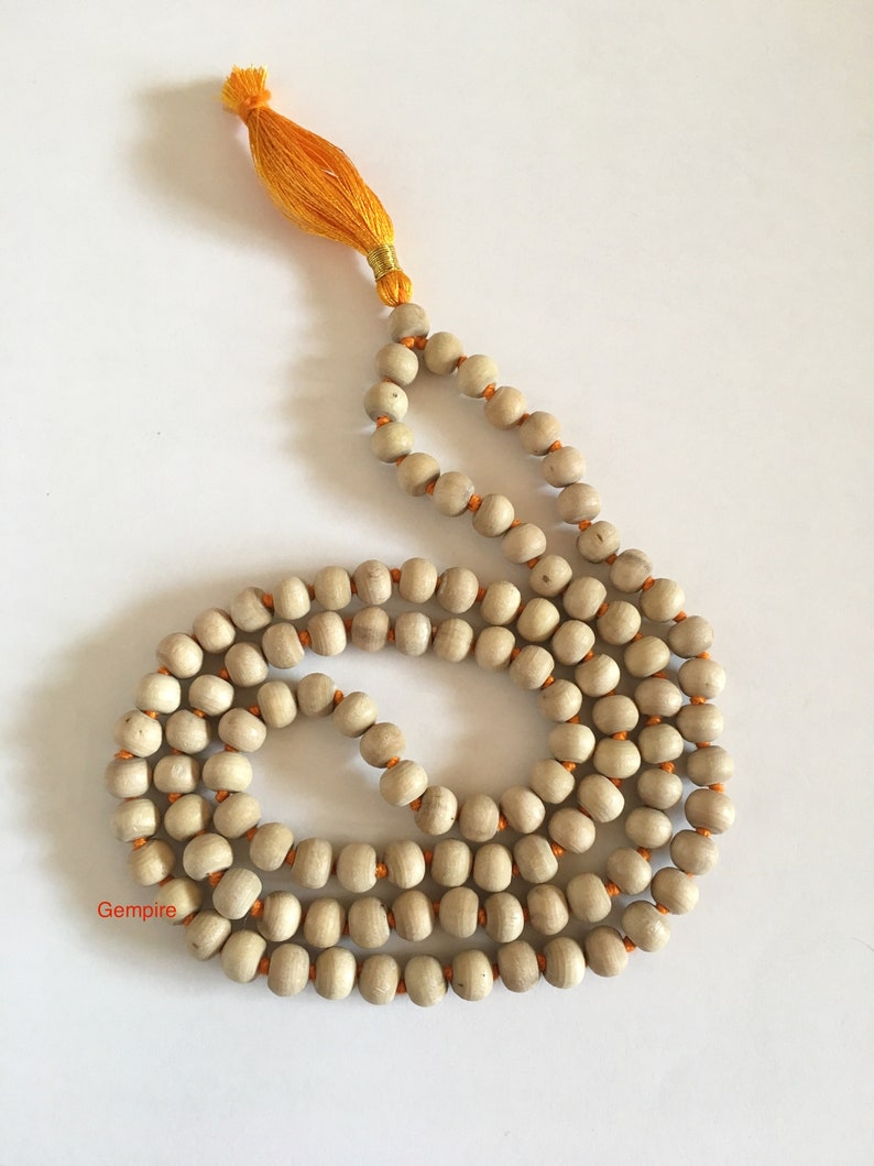 Pu&ograve; includere: Una collana di perline mala in legno di colore chiaro con filo arancione e un nappa gialla. Le perline sono lisce e rotonde, e la nappa &egrave; fatta di fili sottili. La collana viene probabilmente utilizzata per la meditazione o pratiche spirituali.