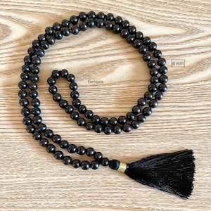 May include: Black wooden beaded necklace with a black tassel. The beads are 8 mm in diameter. Gempire.