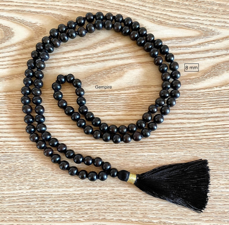 May include: Black wooden beaded necklace with a black tassel. The beads are 8 mm in diameter. Gempire.