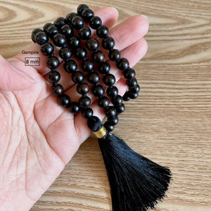 May include: Black wooden beaded necklace with a black tassel. The beads are 8 mm in diameter. Gemspire.