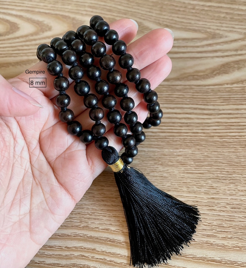 May include: Black wooden beaded necklace with a black tassel. The beads are 8 mm in diameter. Gemspire.
