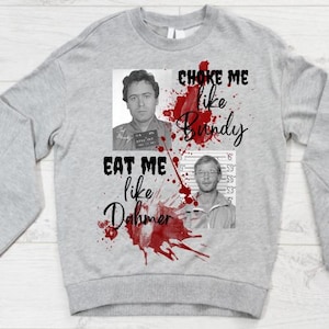 Op de afbeelding: Een lichtgrijs sweatshirt met twee zwart-wit foto's. De tekst "CHOKE ME like Bundy" en "EAT ME like Dahmer" is geschreven in zwart script met rode bloedspatten.