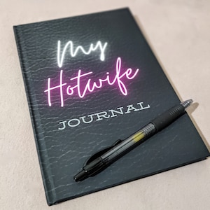 May include: Black leather-bound journal with the text "my hotwife journal" in white and pink neon lettering.