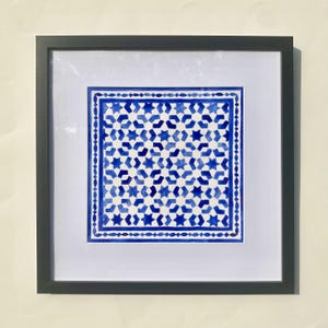 Op de afbeelding: Een ingelijst aquarel schilderij van een geometrisch patroon in blauw en wit. Het patroon bestaat uit herhalende sterren en vierkanten.