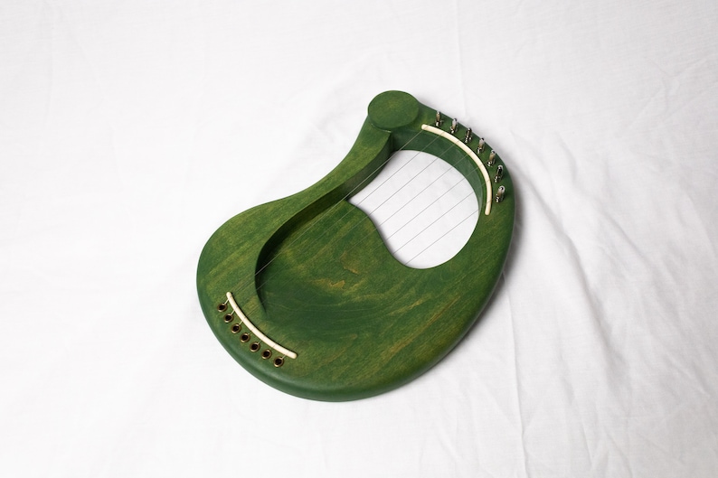 May include: A green wooden lyre with strings and gold tuning pegs.