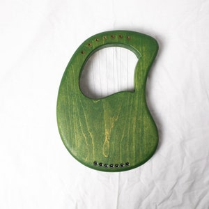 May include: A green wooden lyre with strings, a traditional musical instrument.