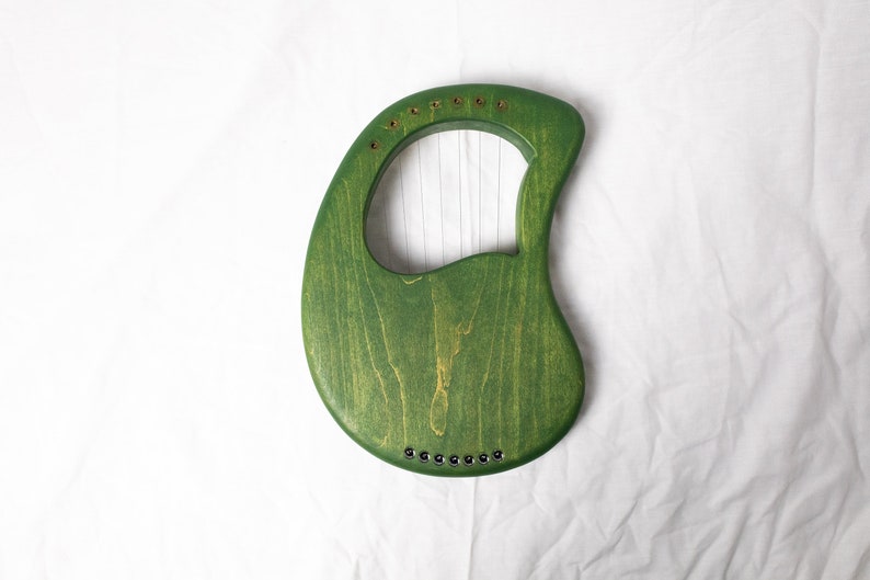May include: A green wooden lyre with strings, a traditional musical instrument.