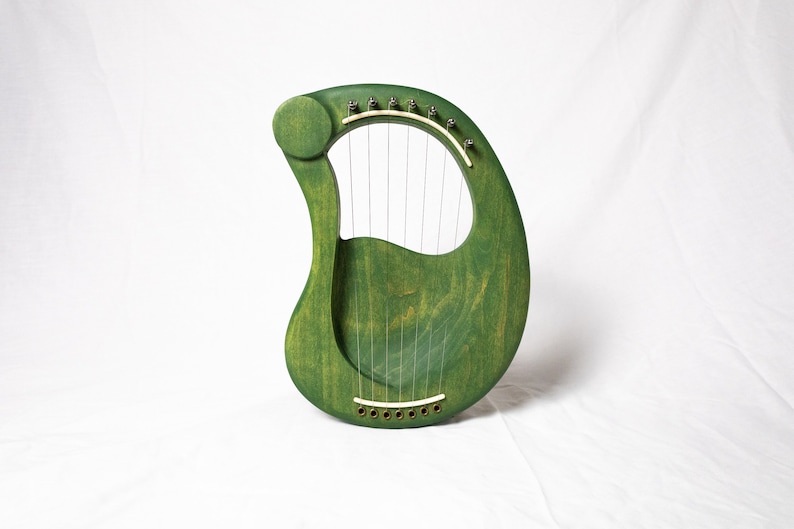 May include: A green wooden lyre with strings and a sound hole. The lyre is a musical instrument.