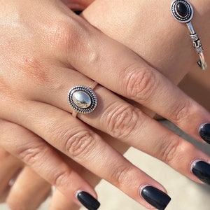 Può includere: Un anello d'argento con una pietra ovale nera e un braccialetto d'argento con tre pietre ovali nere.