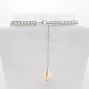 May include: A silver chain necklace with a white seashell pendant.