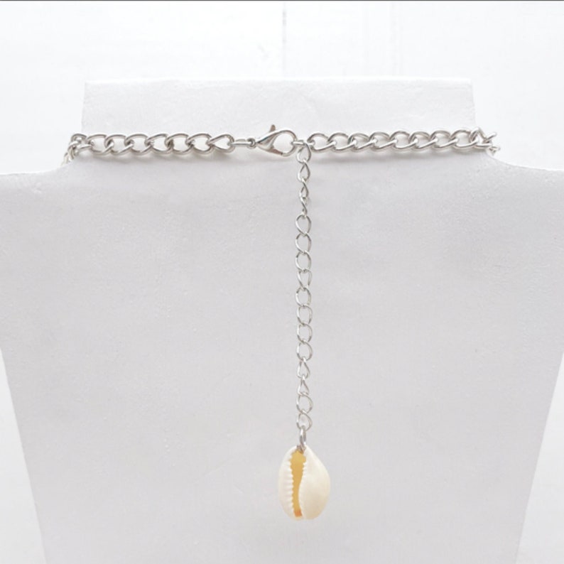 May include: A silver chain necklace with a white seashell pendant.