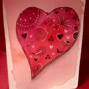 May include: A watercolour painting of a red heart with detailed patterns. The heart features paisley, floral, and heart-shaped designs, set against a soft pink background. The artwork is on a rectangular card.