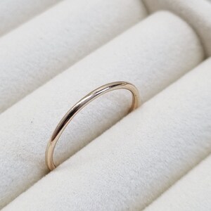 May include: A simple, thin gold band ring in a ring box.