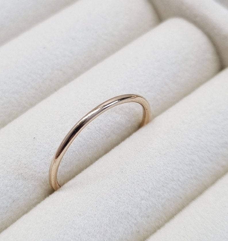 May include: A simple, thin gold band ring in a ring box.